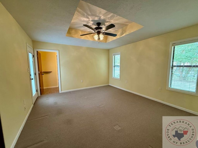 unfurnished room with ceiling fan, carpet, and a tray ceiling