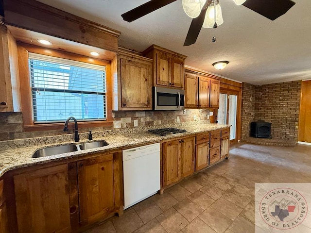 kitchen with dishwasher, ceiling fan, sink, tasteful backsplash, and a wood stove