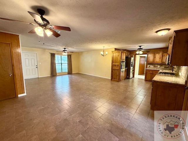 kitchen featuring ceiling fan with notable chandelier, a textured ceiling, decorative light fixtures, stainless steel appliances, and tasteful backsplash