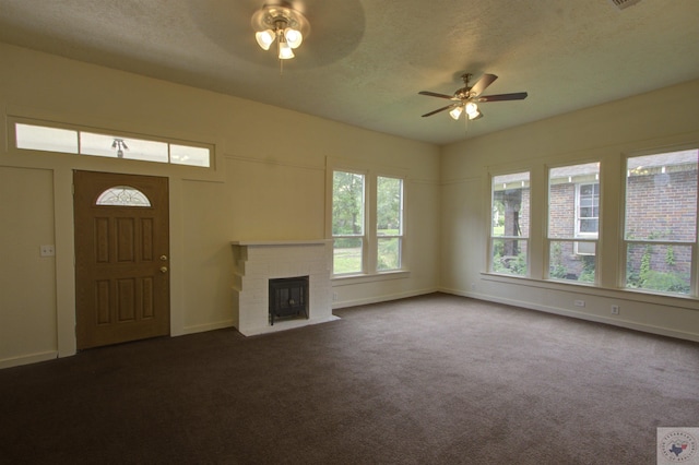 unfurnished living room with a fireplace, dark carpet, a textured ceiling, and ceiling fan