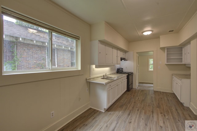 kitchen featuring white cabinets, black electric range oven, a healthy amount of sunlight, and light hardwood / wood-style floors