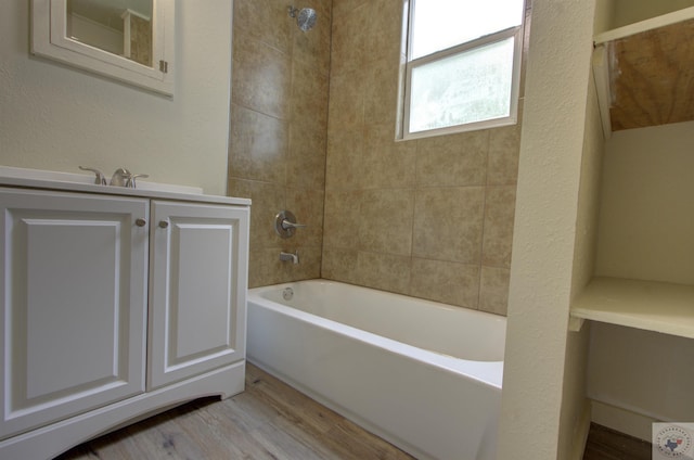 bathroom featuring hardwood / wood-style floors, tiled shower / bath combo, and vanity