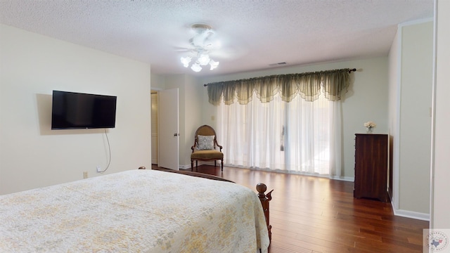 bedroom featuring visible vents, baseboards, a textured ceiling, and wood finished floors