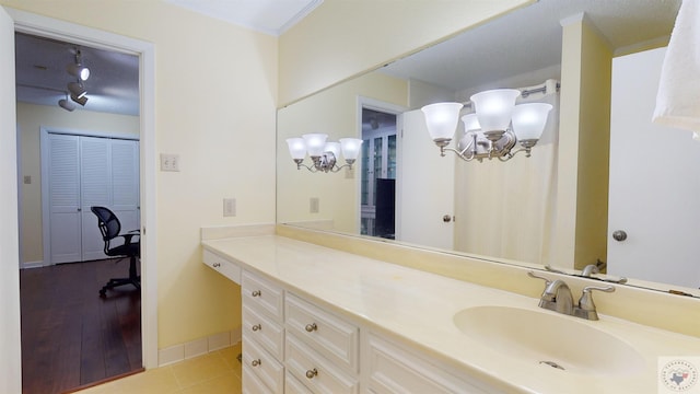 bathroom with vanity, crown molding, baseboards, and tile patterned flooring