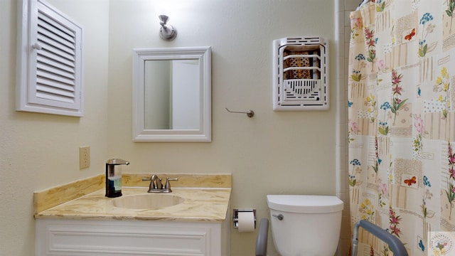 bathroom featuring curtained shower, toilet, and vanity