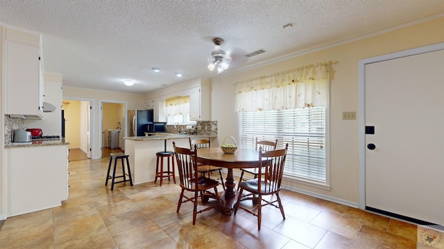 dining space featuring visible vents, a textured ceiling, baseboards, and a ceiling fan