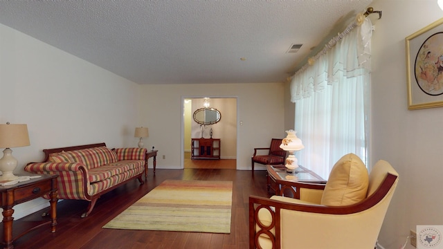 living area featuring baseboards, wood finished floors, visible vents, and a textured ceiling