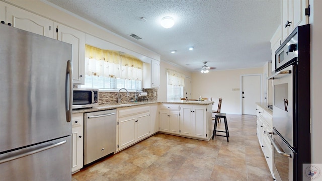 kitchen featuring white cabinetry, a peninsula, appliances with stainless steel finishes, and a sink