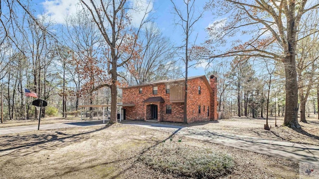 view of front of house with concrete driveway, brick siding, and a chimney