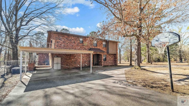 view of front of home featuring driveway, cooling unit, a carport, and brick siding