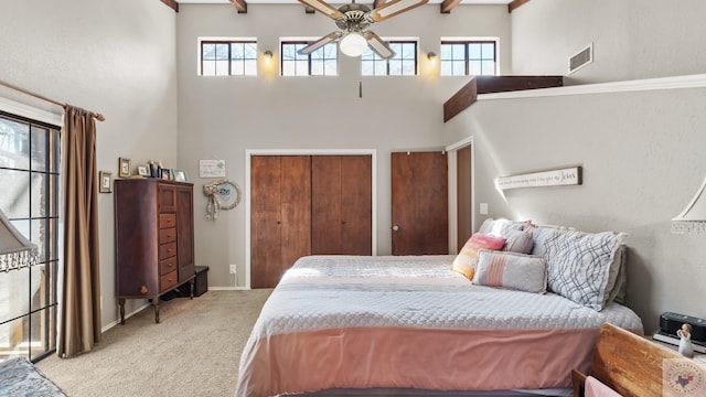 carpeted bedroom with a towering ceiling, baseboards, visible vents, and two closets