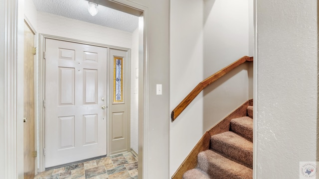 entryway featuring stone finish flooring, stairway, and a textured ceiling