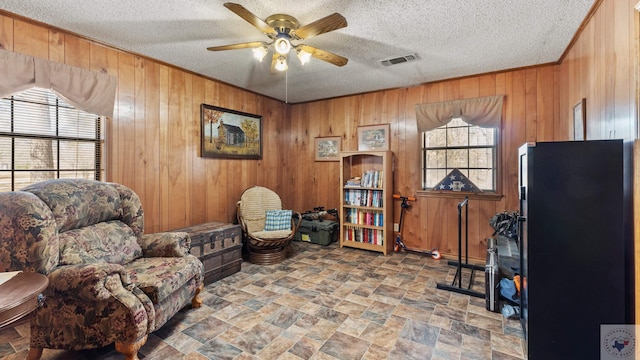 living area with a wealth of natural light, visible vents, and wooden walls