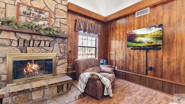 sitting room with wood walls, a fireplace, visible vents, and wood finished floors