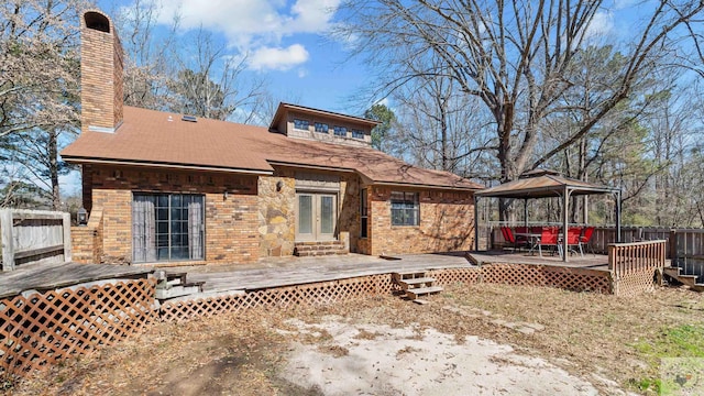 back of house with a deck, brick siding, a gazebo, french doors, and a chimney