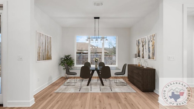 dining room featuring baseboards, wood finished floors, visible vents, and an inviting chandelier