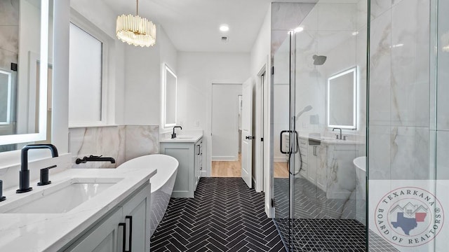 full bath with a sink, a shower stall, and a freestanding bath