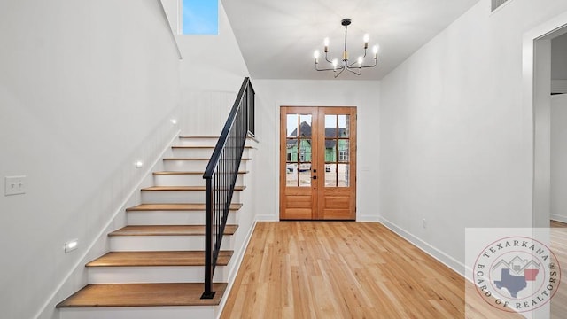 entryway featuring french doors, stairway, an inviting chandelier, light wood-style floors, and baseboards