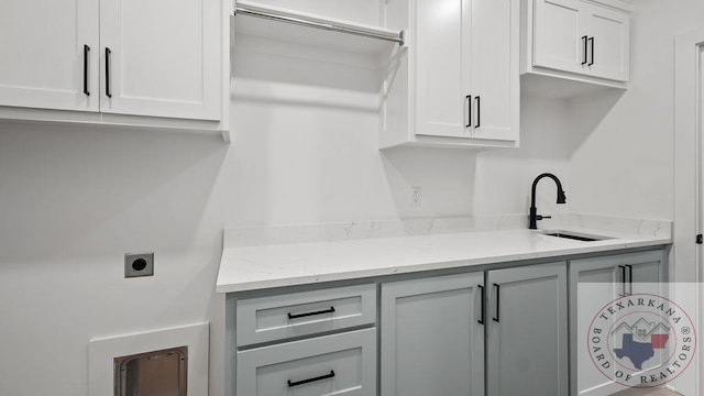 clothes washing area with hookup for an electric dryer, cabinet space, and a sink