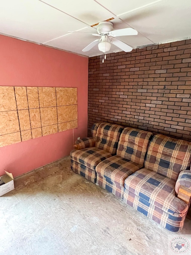 unfurnished living room featuring brick wall and ceiling fan