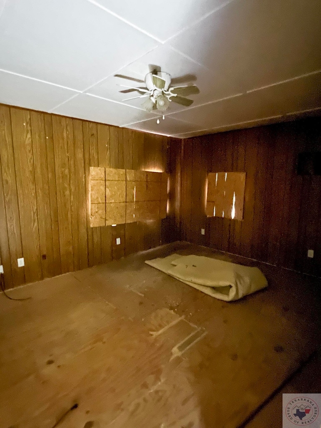 unfurnished room featuring ceiling fan and wood walls