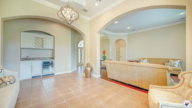 1067 Beaver Lake Dr, Texarkana, TX 75501 - living area with beverage cooler, arched walkways, wet bar, a chandelier, and ornamental molding