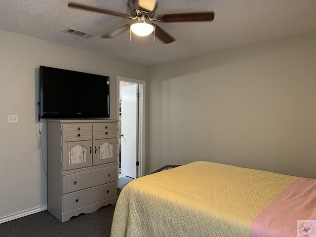 bedroom featuring ceiling fan, dark carpet, and a textured ceiling