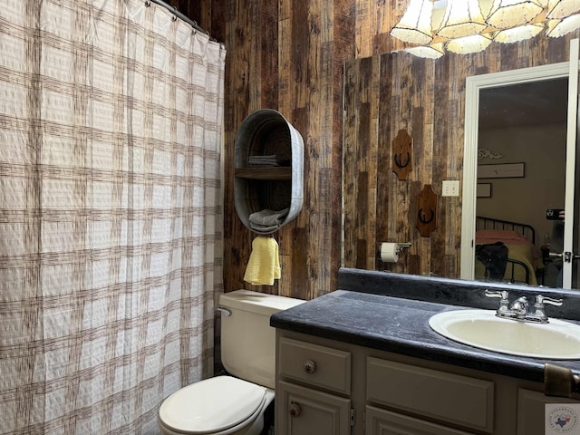 bathroom with vanity, toilet, and wooden walls