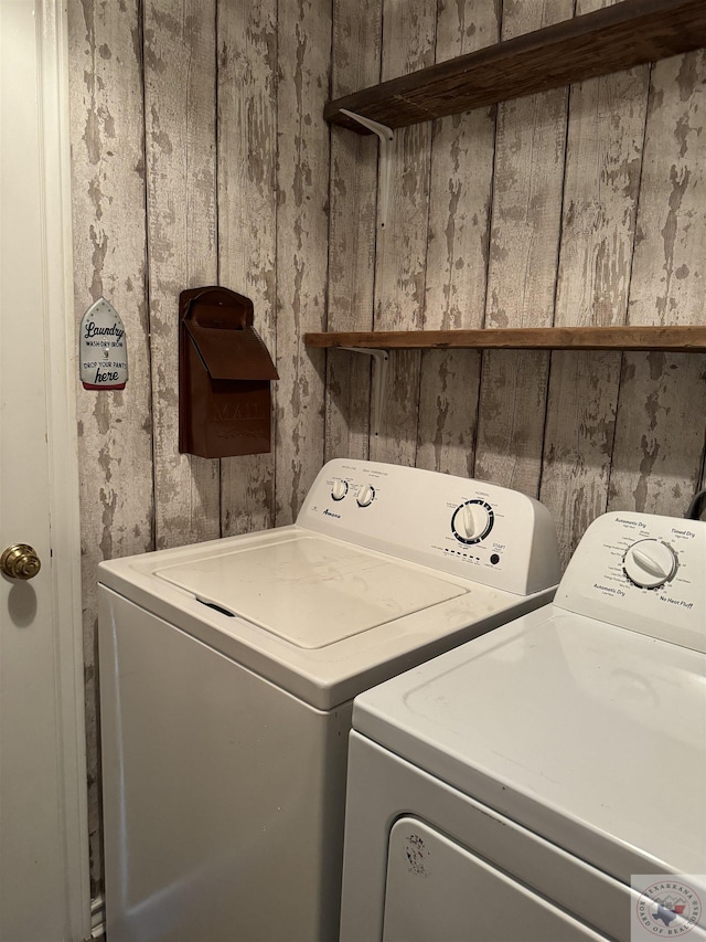 laundry area featuring wood walls and separate washer and dryer