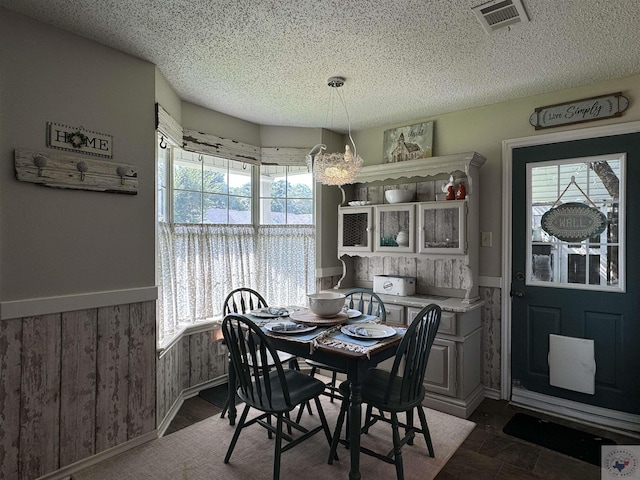 dining space featuring wood walls and a textured ceiling