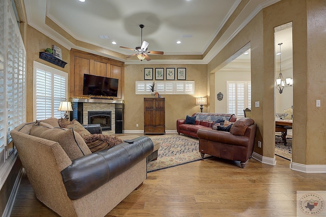 living room featuring light hardwood / wood-style floors, crown molding, and ceiling fan with notable chandelier