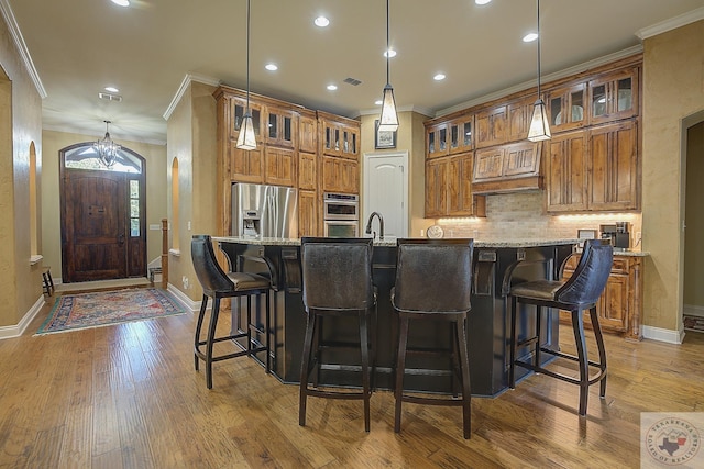 kitchen featuring ornamental molding, light stone counters, a large island, and stainless steel appliances