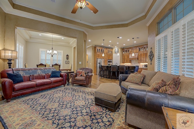 living room with ceiling fan with notable chandelier and ornamental molding