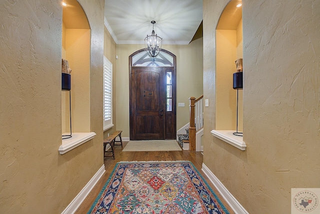 foyer with hardwood / wood-style flooring, a chandelier, and crown molding