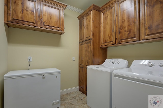 laundry area with washing machine and dryer, crown molding, and cabinets