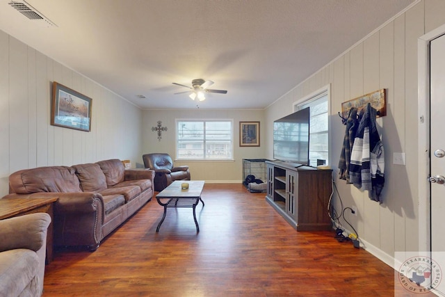 living room featuring dark wood-type flooring, ornamental molding, and ceiling fan