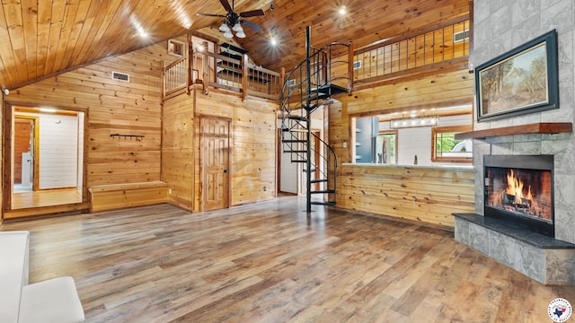 77 Big Rock Cir, Texarkana, AR 71854 - unfurnished living room with stairs, wood walls, a fireplace, ceiling fan, and wood finished floors