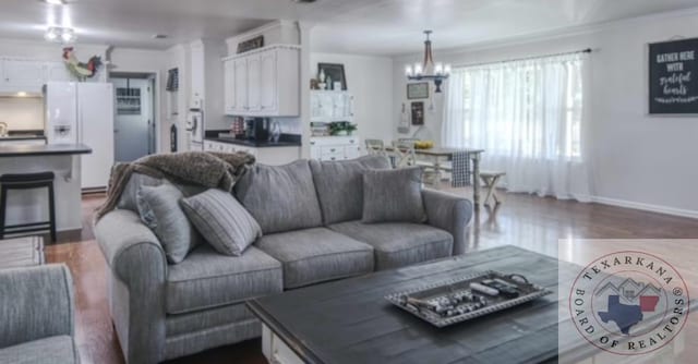 living room with dark wood-type flooring, ornamental molding, and a notable chandelier