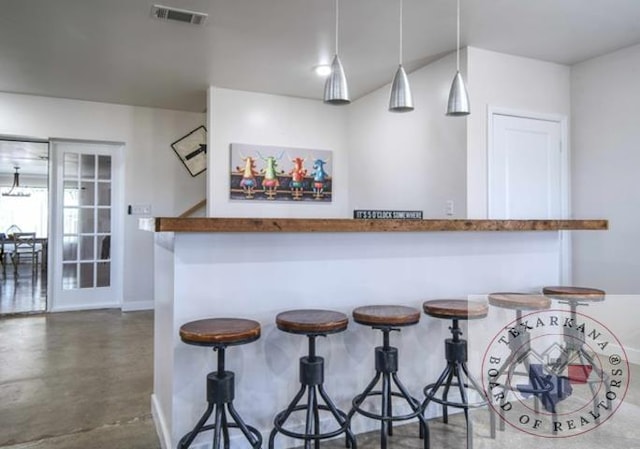 kitchen with decorative light fixtures, a breakfast bar, and kitchen peninsula