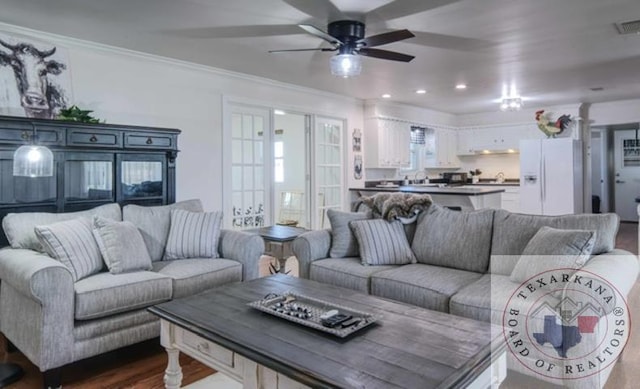 living room with hardwood / wood-style flooring, crown molding, and ceiling fan