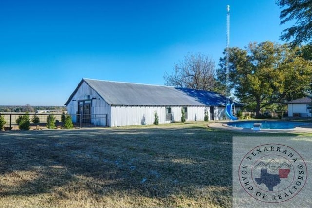 view of outbuilding featuring a fenced in pool and a yard