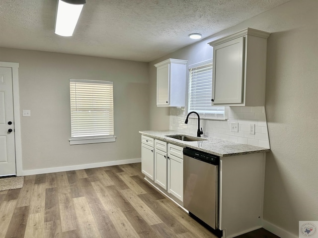 kitchen featuring light stone countertops, white cabinets, dishwasher, tasteful backsplash, and sink