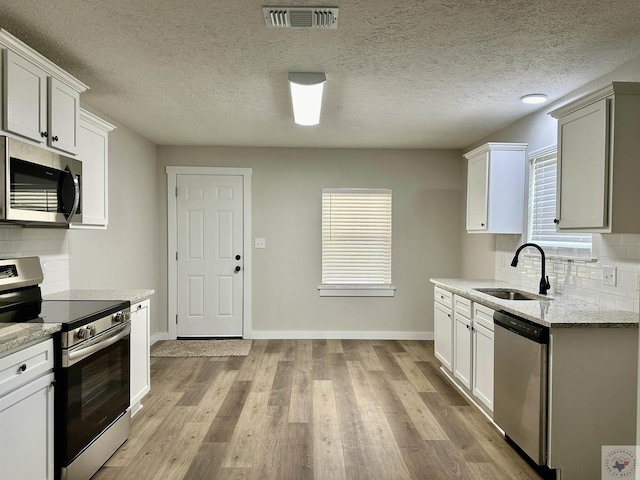 kitchen featuring sink, stainless steel appliances, white cabinets, and decorative backsplash