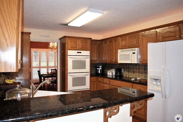 6002 Forest Bnd, Texarkana, AR 71854 - kitchen with white appliances, a peninsula, backsplash, a chandelier, and dark stone counters