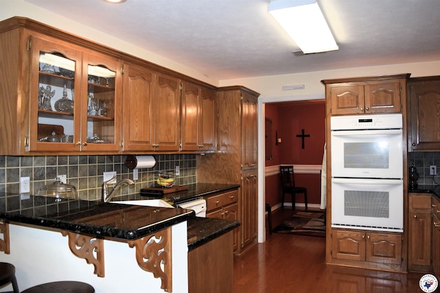 6002 Forest Bnd, Texarkana, AR 71854 - kitchen with double oven, a peninsula, a kitchen breakfast bar, glass insert cabinets, and tasteful backsplash