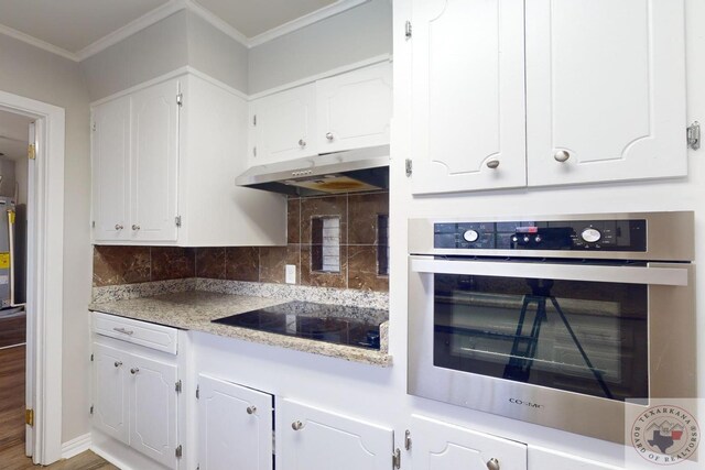 kitchen with black electric cooktop, backsplash, stainless steel oven, and white cabinets