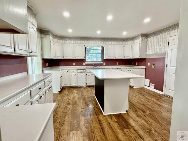 kitchen with sink, wood-type flooring, white cabinets, and a kitchen island