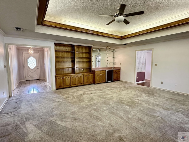 unfurnished living room with carpet, a tray ceiling, and ornamental molding