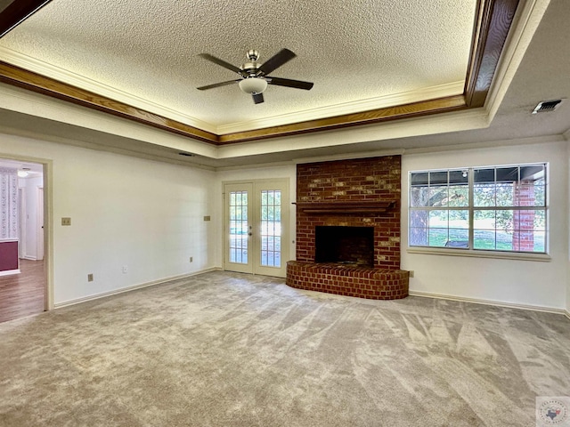 unfurnished living room featuring a healthy amount of sunlight, carpet flooring, a tray ceiling, and ornamental molding