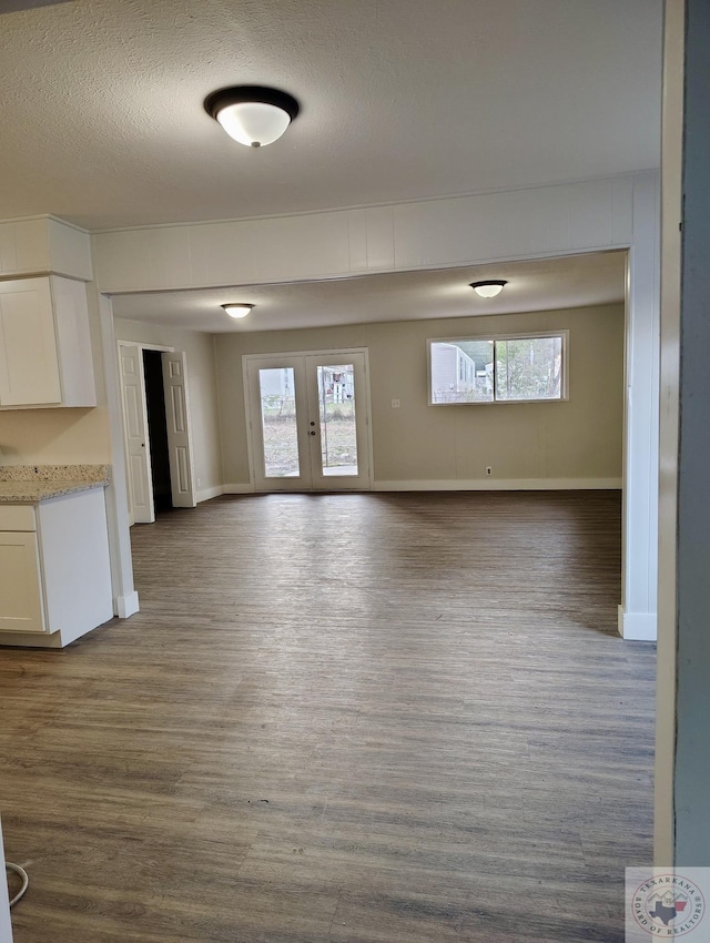 unfurnished living room featuring french doors, light hardwood / wood-style flooring, and a textured ceiling